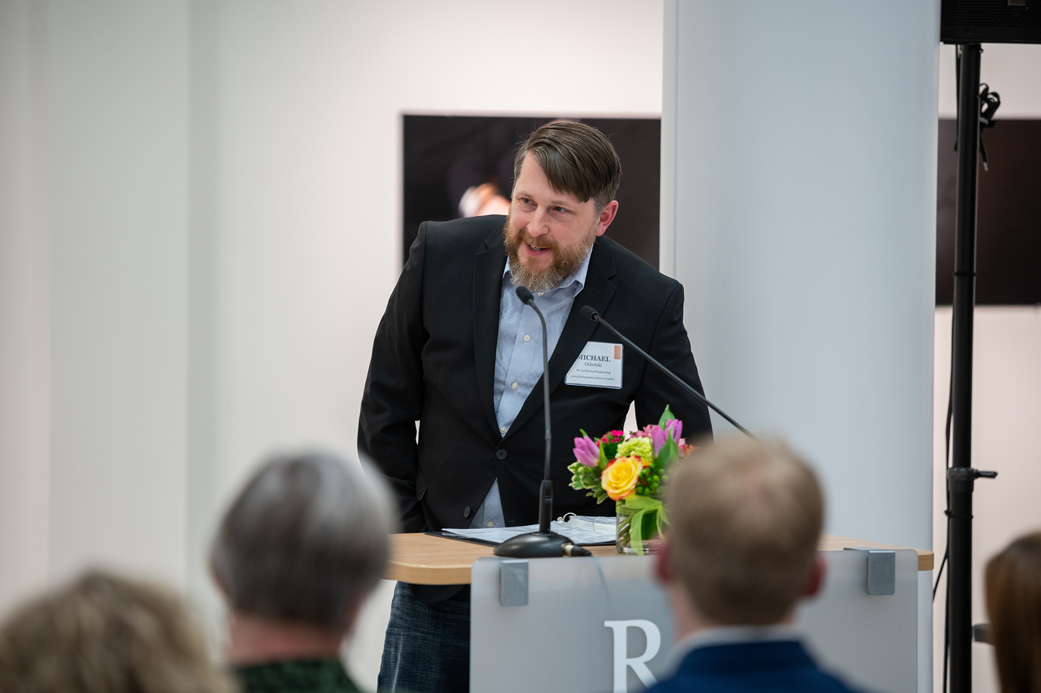 Michael Oshetski accepts the Kate Gleason College of Engineering Distinguished Alumni Award at a podium while speaking into a microphone.