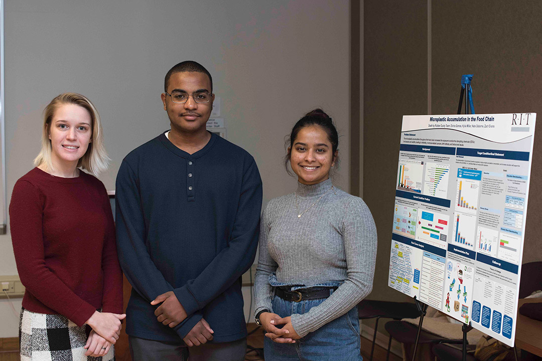 three students posing next to poster presentation.