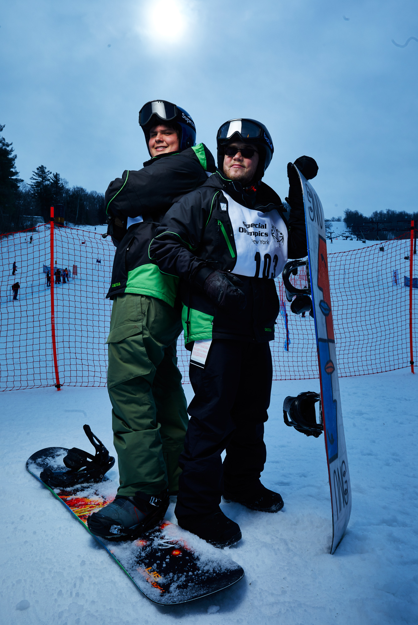 Two snowboarders stand back to back