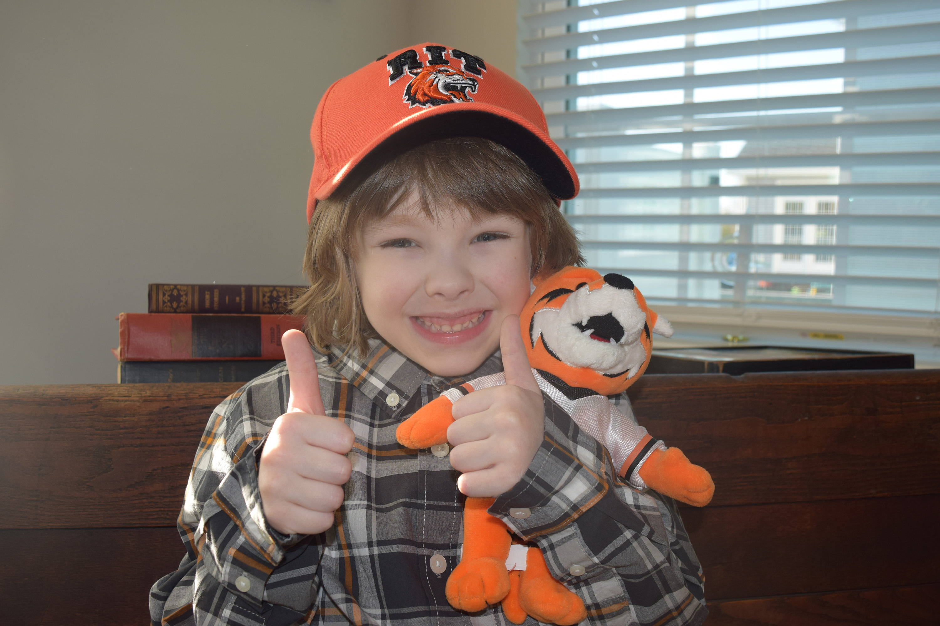 A photo of a boy wearing an RIT hat giving thumbs up.