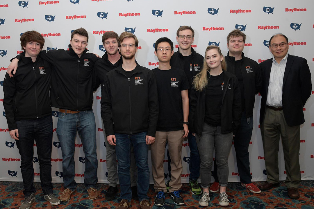 Team of students stands against backdrop.