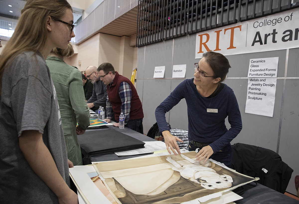 Faculty Emily Glass reviews a student's portfolio.