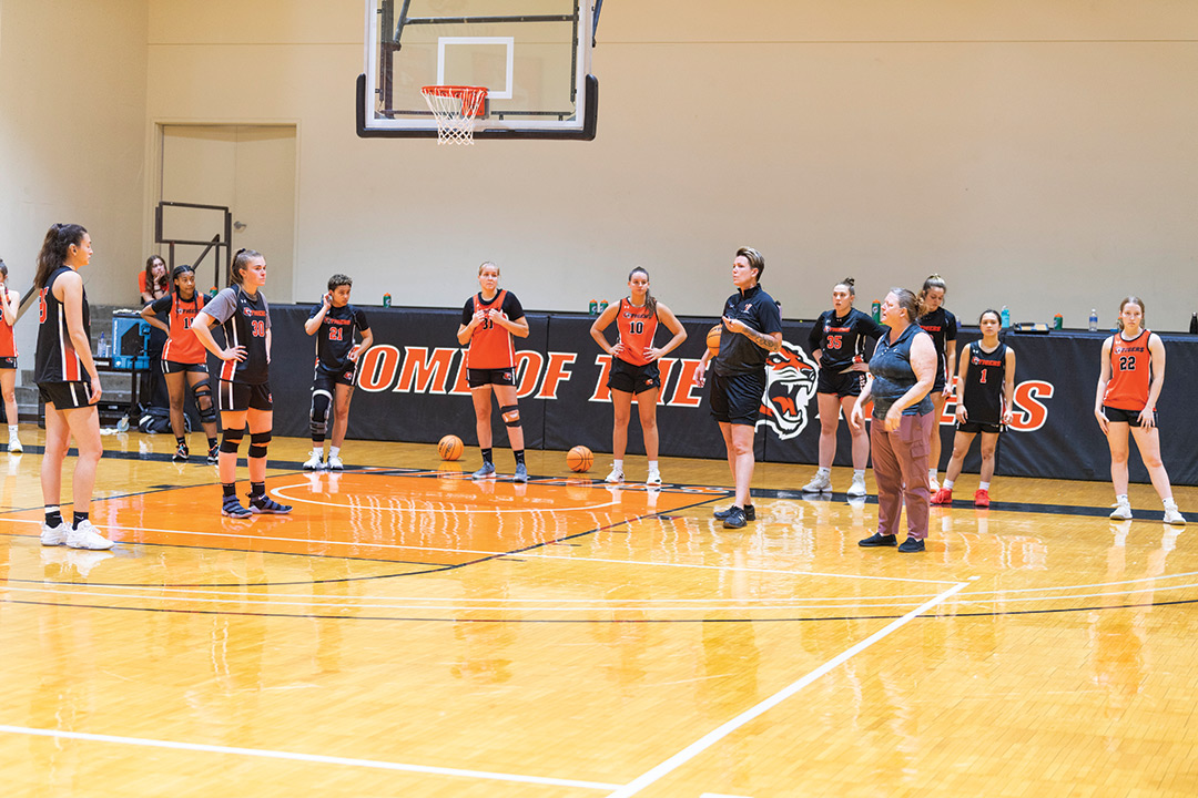 basketball players and coach standing on a basketball court during practice.