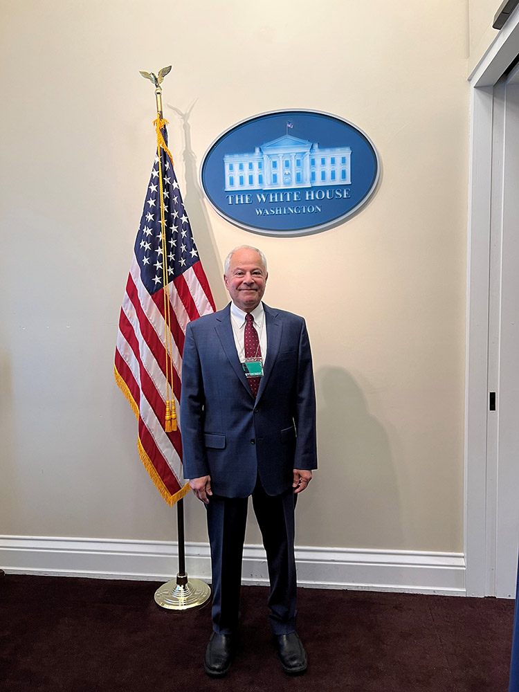 man standing next to an American flag in the White House.