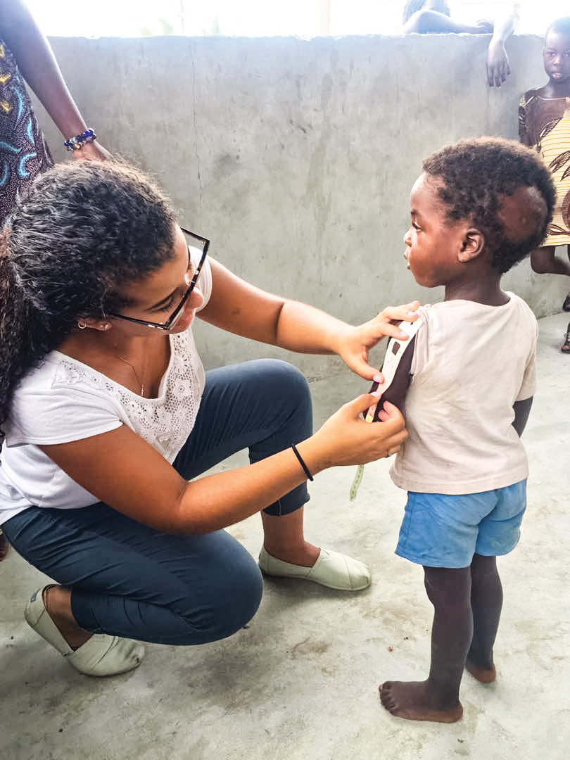 Woman kneels next to standing child while apply monitoring strip to his arm.