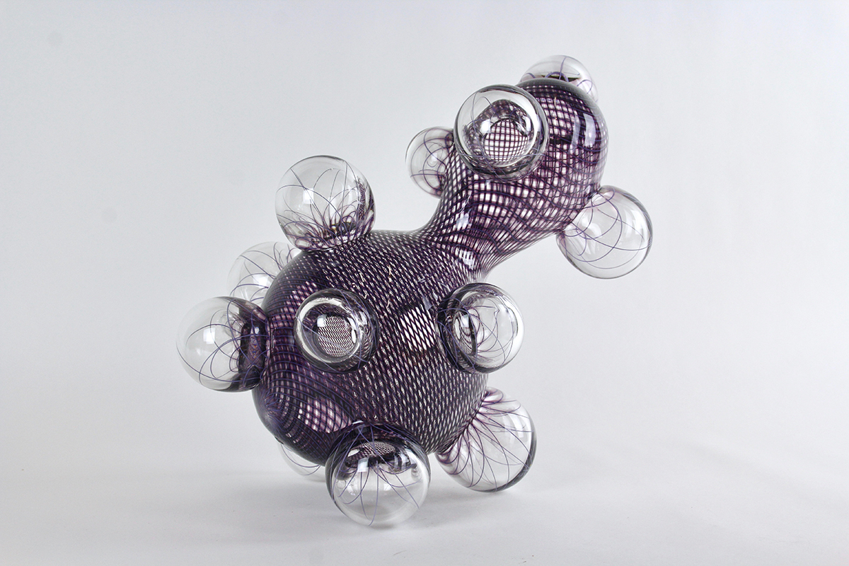 A purple glass work with spheres all around it. 