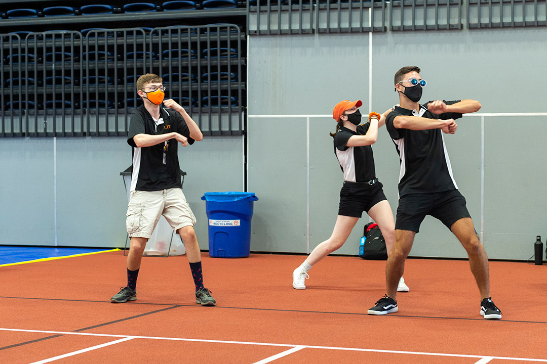 three students wearing masks and dancing.