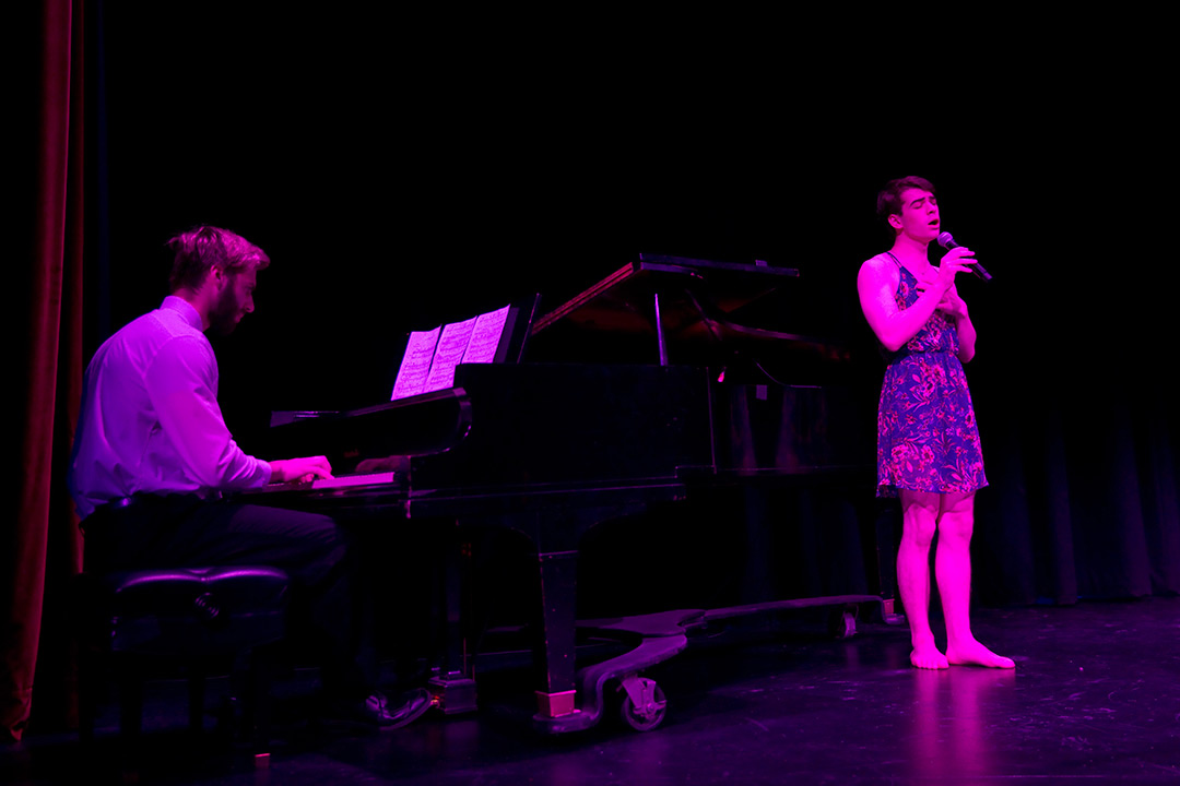 Singer performs while another plays the piano.