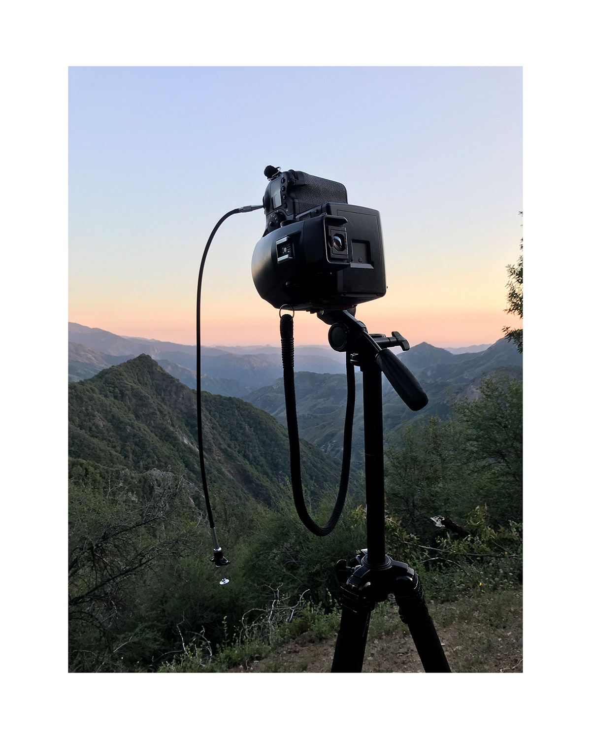 A photo of a video camera set against a mountainous background.