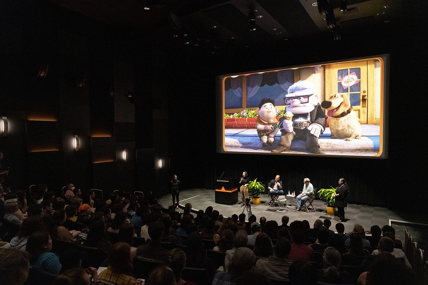A full Wegmans theater watches a presentation by Pete Docter, with a scene from the animated film Up on the screen.