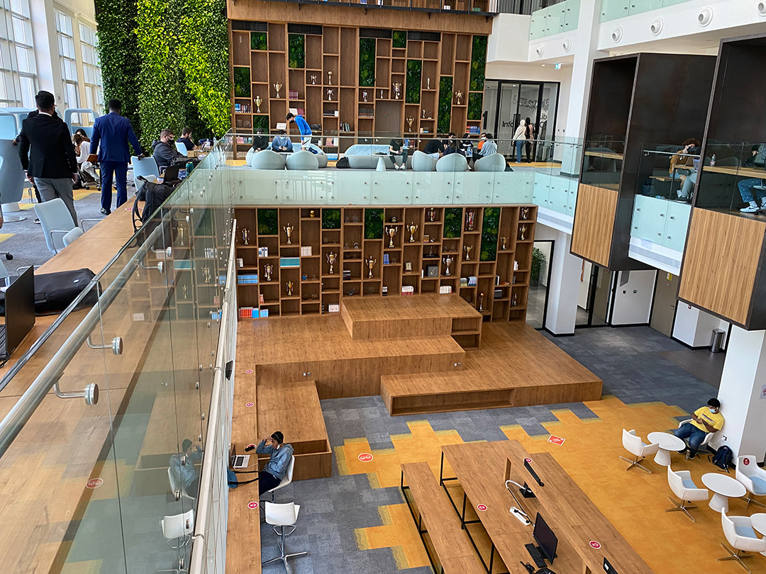 two-level student gathering space with small tables, seating, and a multi-level stage.