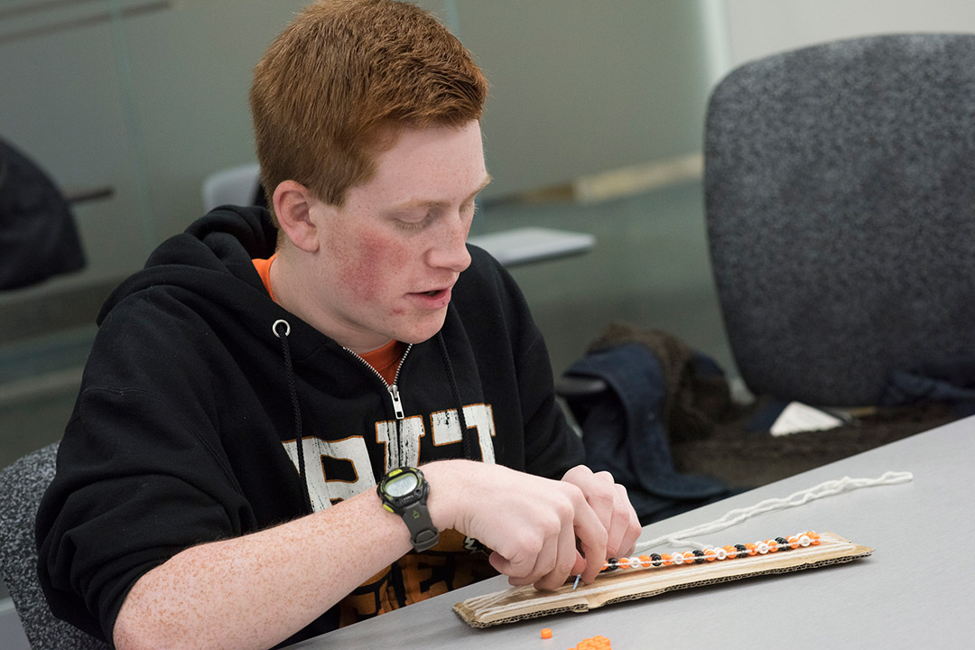 Student makes wampum belt with beads.