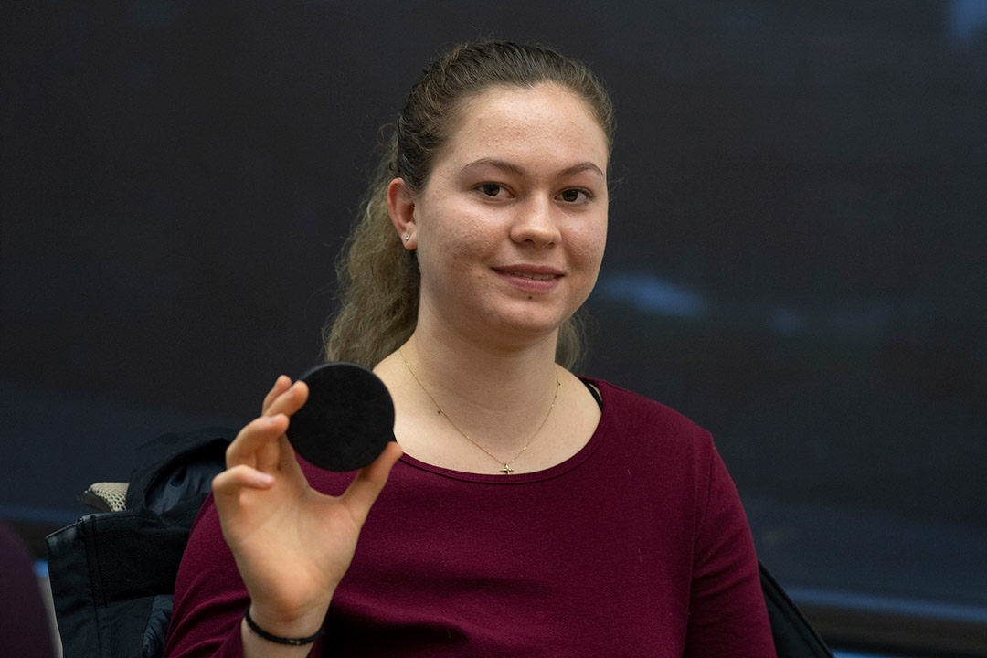 Student holds hockey puck.