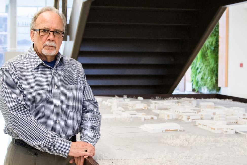 man standing next to table with scale model of RIT campus.