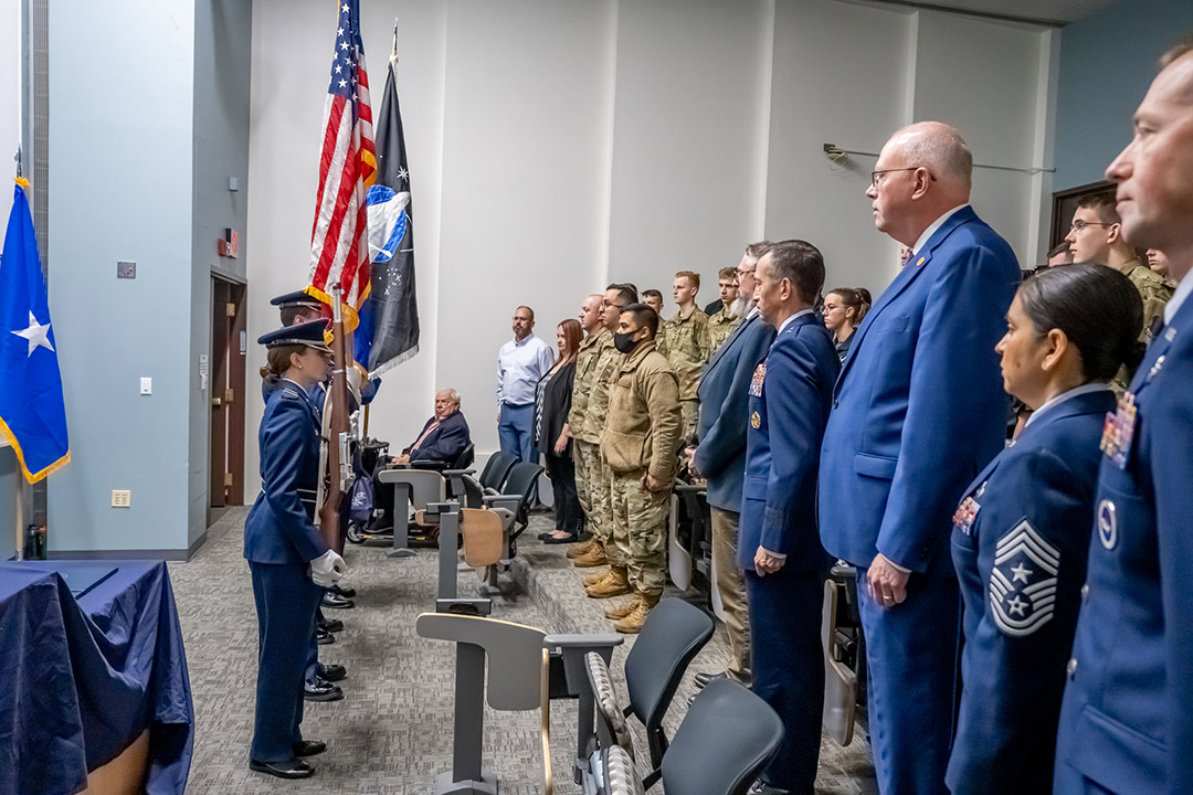 ROTC cadets and officers standing in a room for an award presentation.