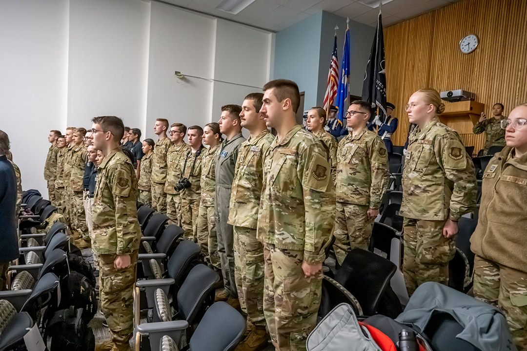 three rows of ROTC cadets standing at attention in an auditorium.