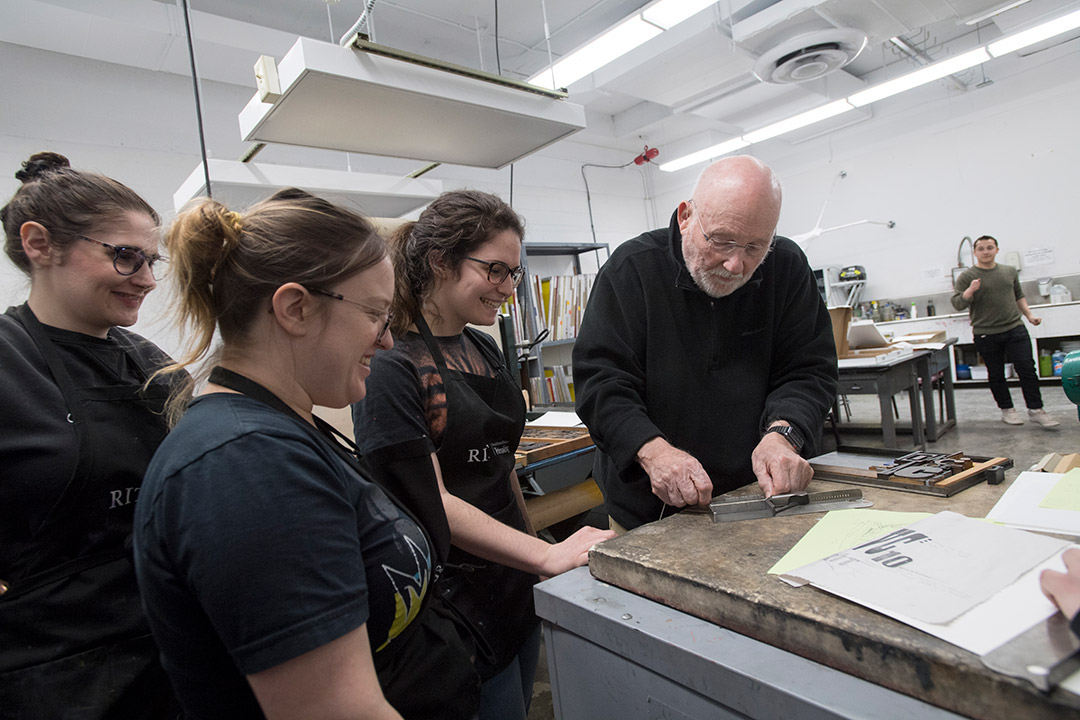 professor working with three students on setting type.