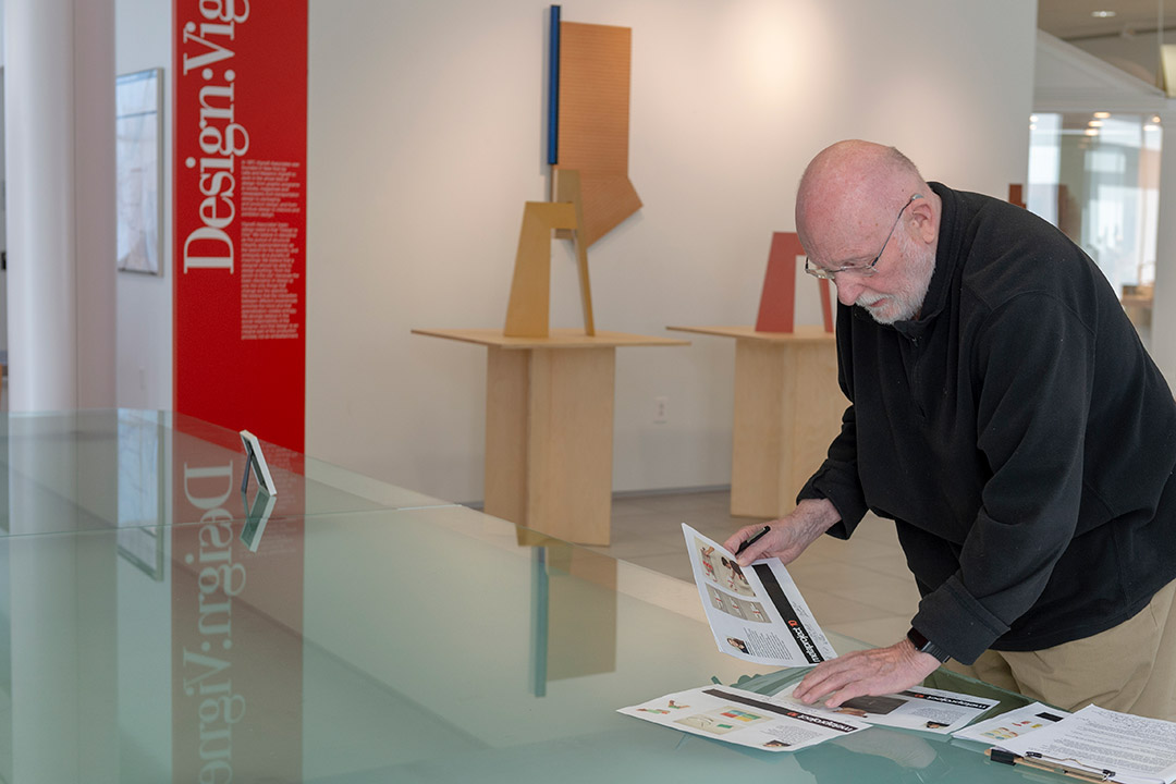 retiring professor looking at printouts on glass table.