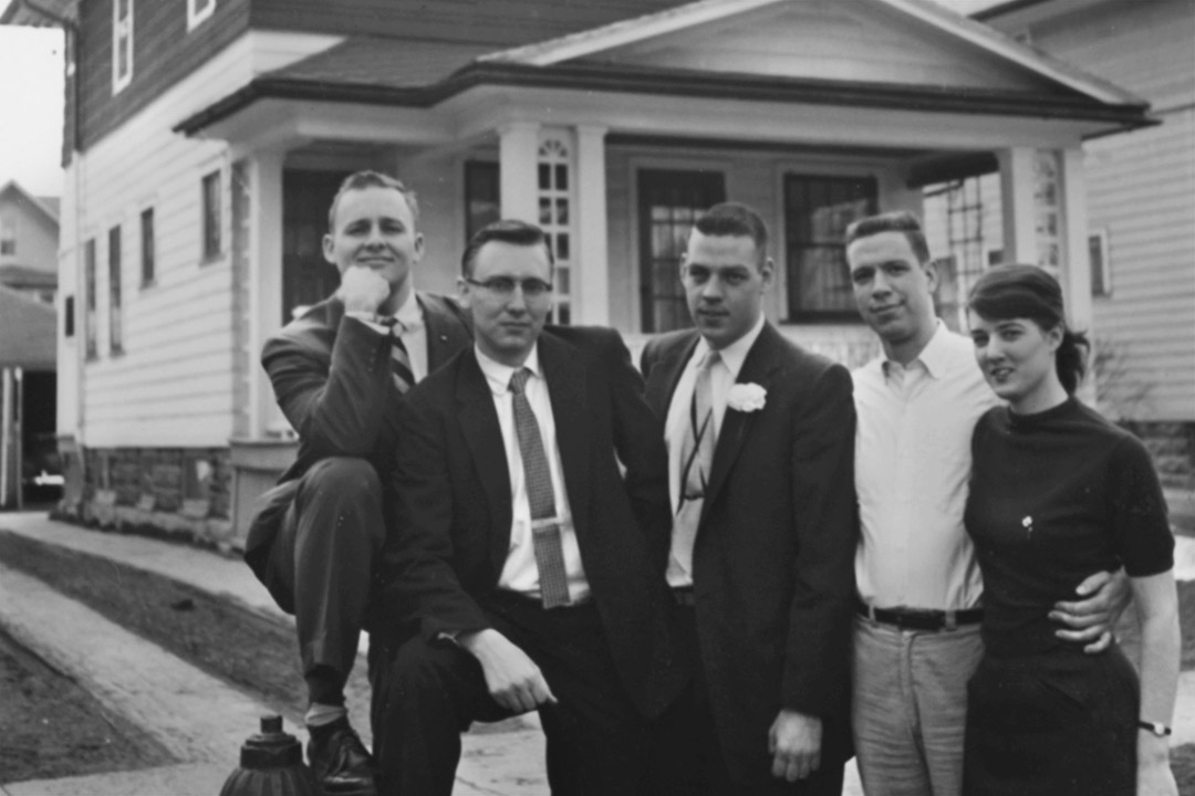 group of five people standing outside of house in 1959.