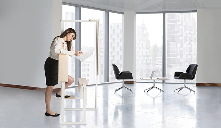 A woman uses the Office Stretcher as she stands and reads from a piece of paper