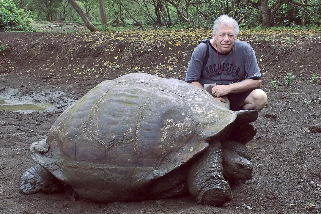 man posing with a giant tortoise in 2017.