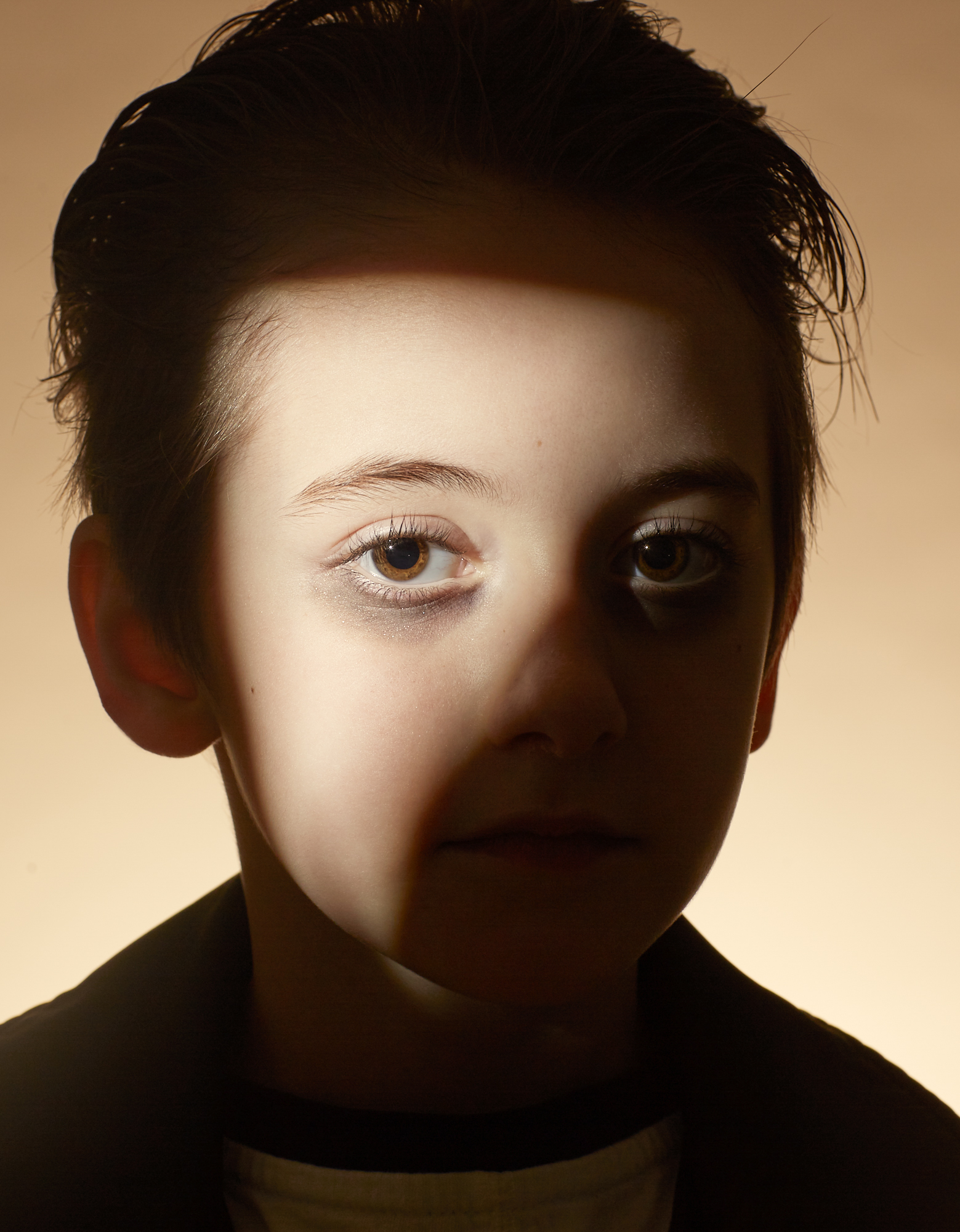 Portrait photography of a boy with light shining on part of his face.