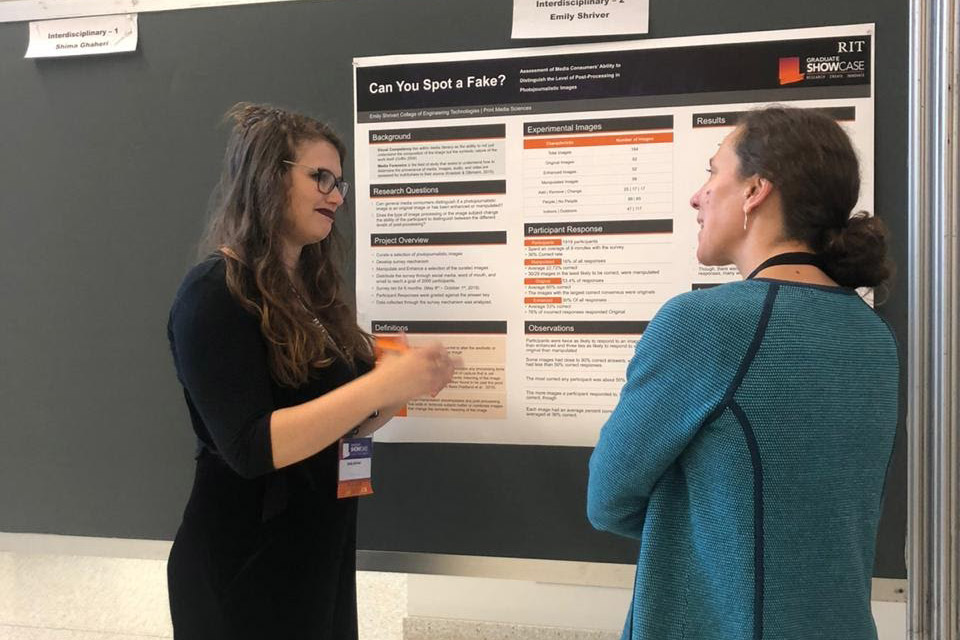 student showing poster presentation to woman.