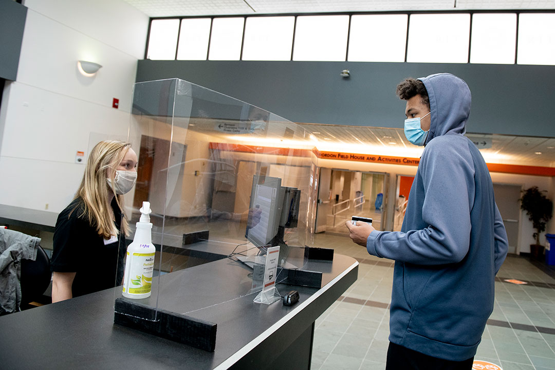 student talking to another student seated at a reception desk.