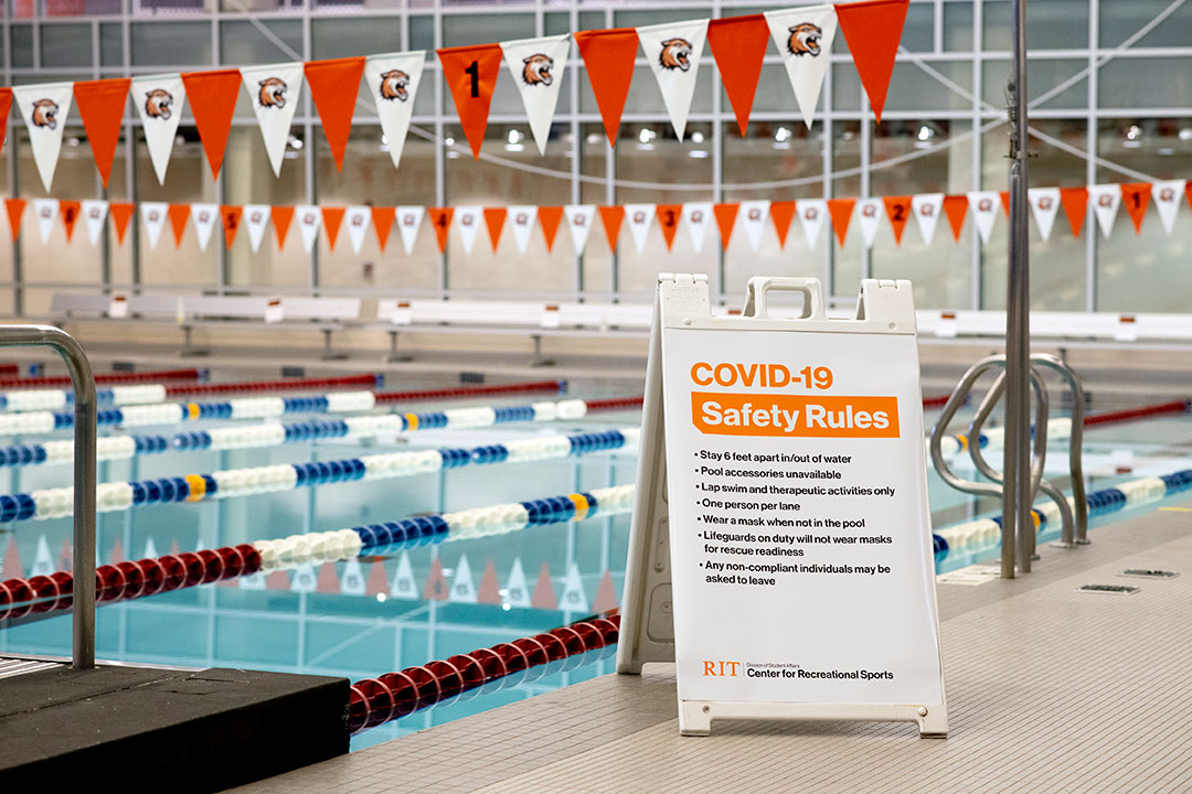 sign with COVID-19 Safety Rules next to indoor swimming pool.