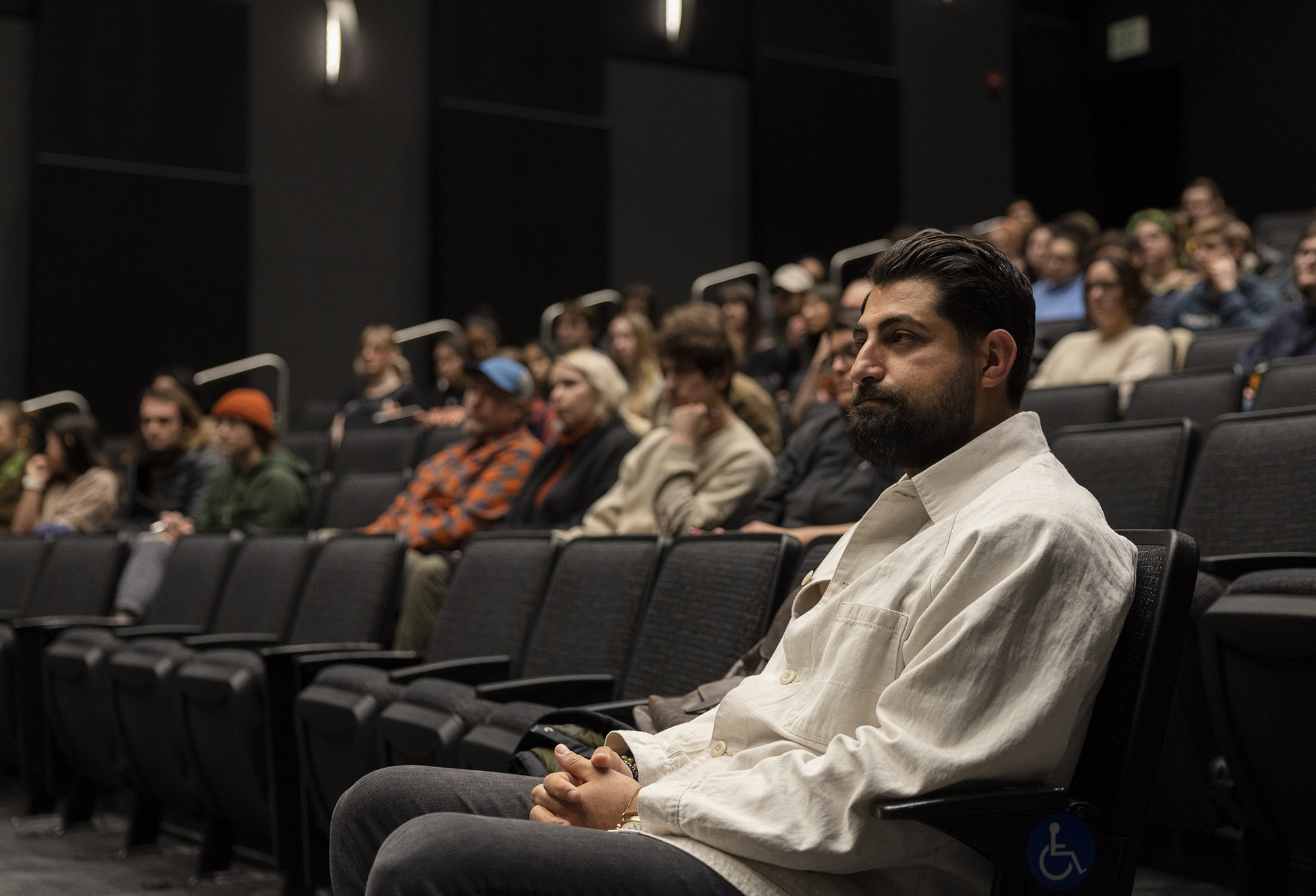 Salwan Georges sits in a theater audience waiting to speak.