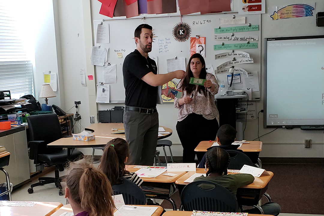 Alumnus and student teach elementary school children.