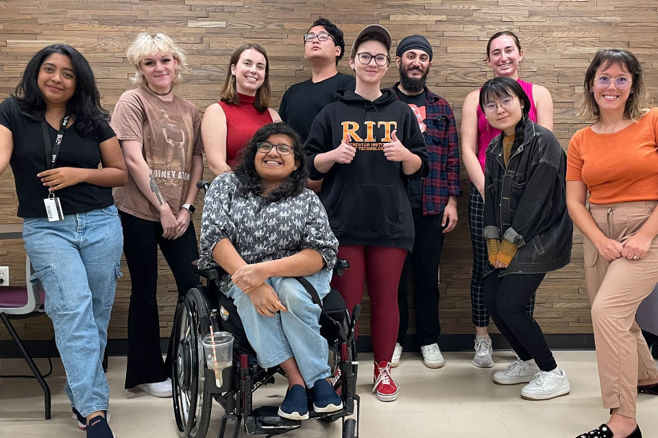 nine college students standing for a photo and one student sitting in a wheelchair.