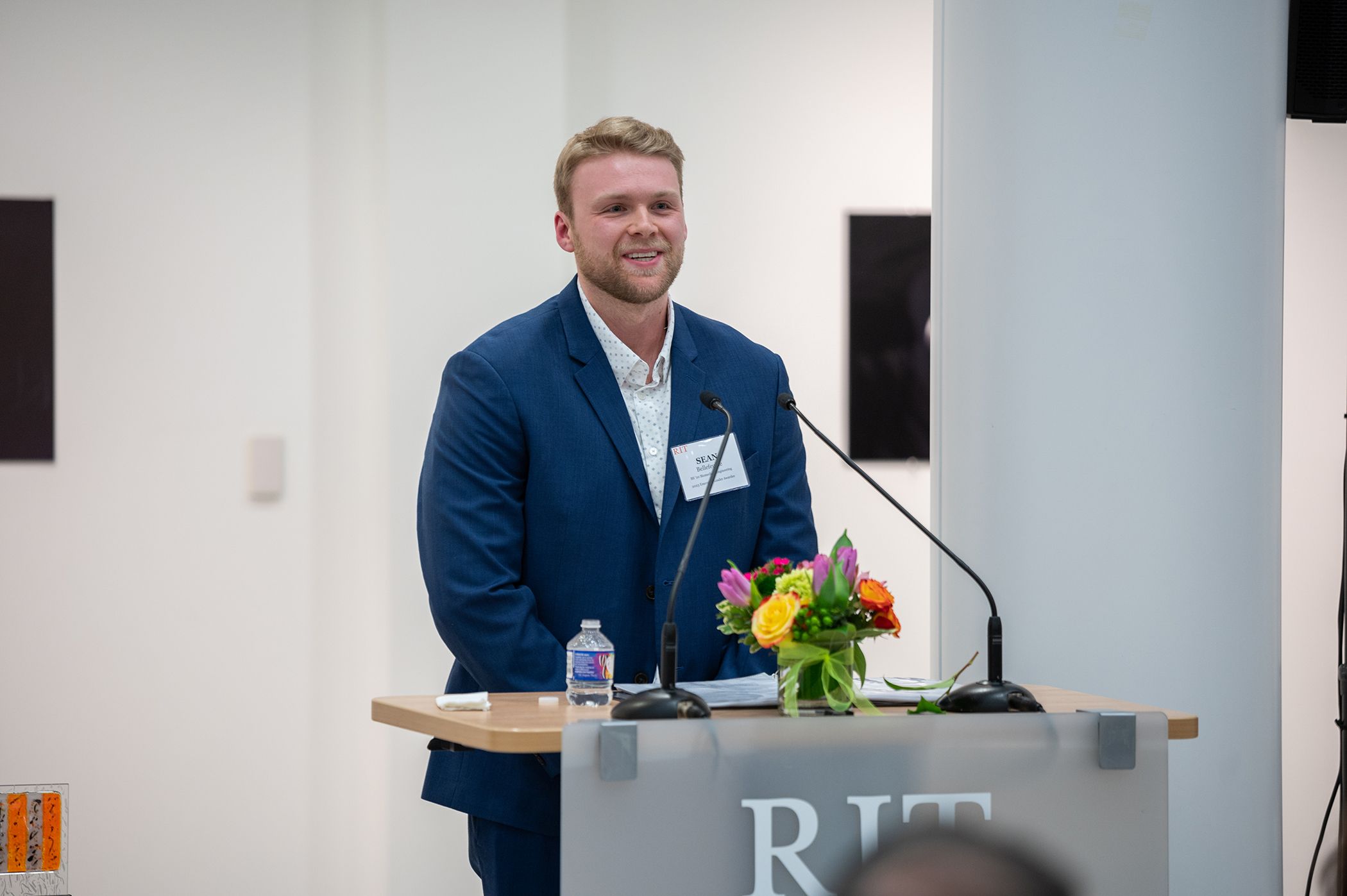 Sean Bellefeuille accepts the Kate Gleason College of Engineering Emerging Leader Award while standing at a podium with a microphone.