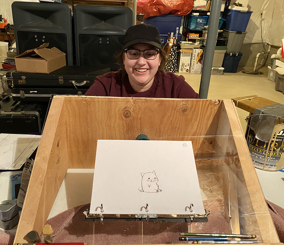 A student models her DIY light table, which is mounted on an old picture frame and boards.