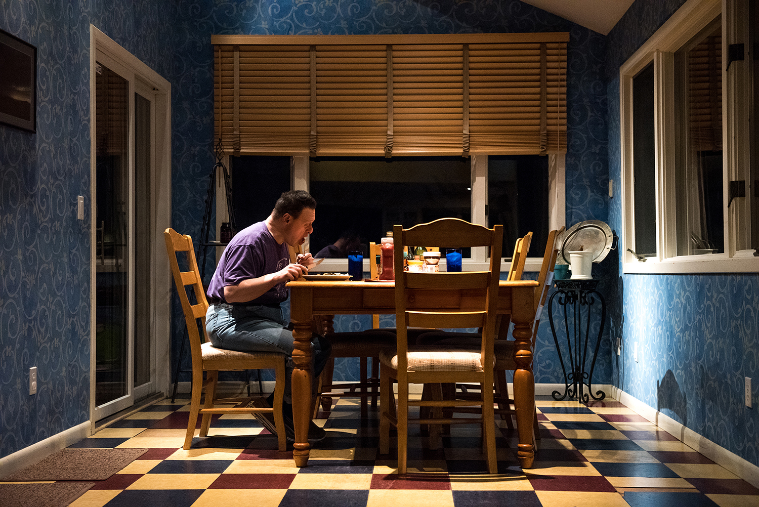 A photo of a man eating at a kitchen table.