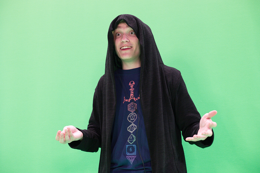 student wearing a black hoodie standing in front of a green screen.