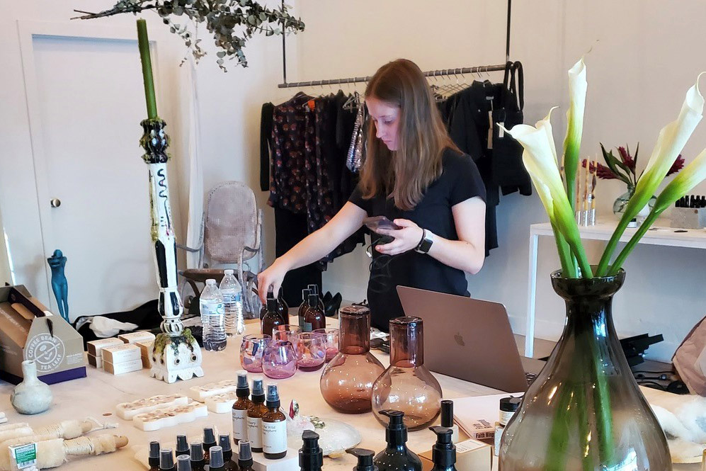 college student placing candle and fragrance products on a table.