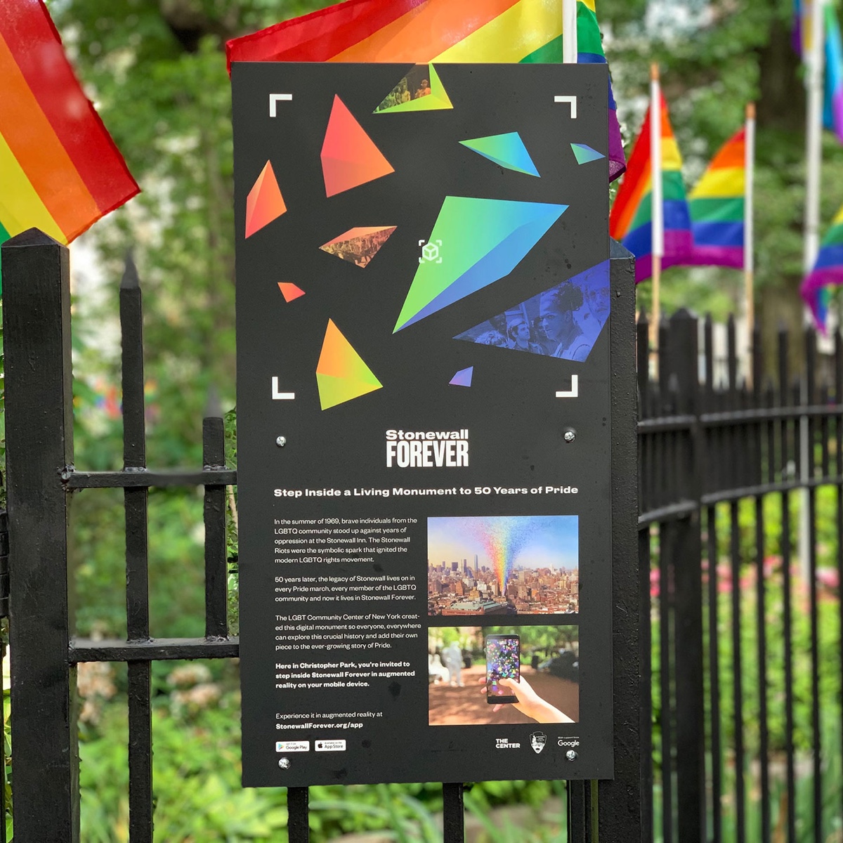 A sign hanging on  fence promoting the Stonewall Forever app. This is one example of Liz's design for good.