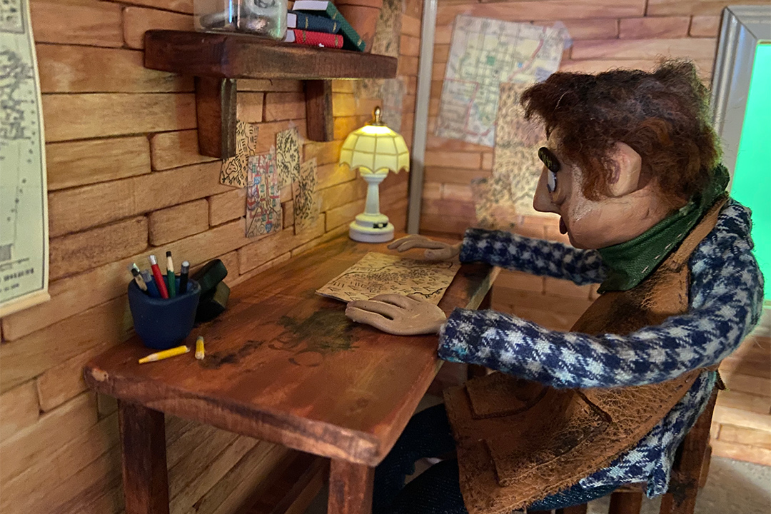 stop-motion scene of a man sitting at a desk looking at a map.