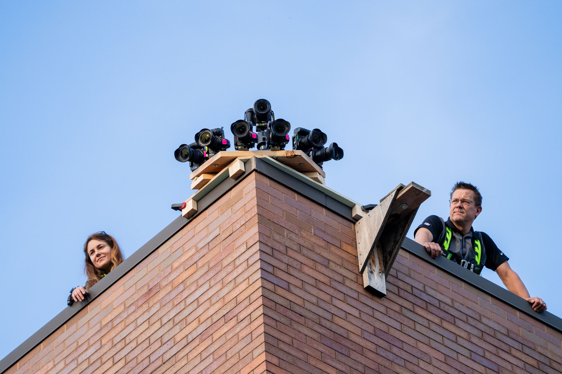 Participants look down from a roof by a setup of cameras