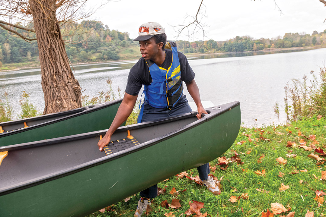 student pulling a canoe along the ground.