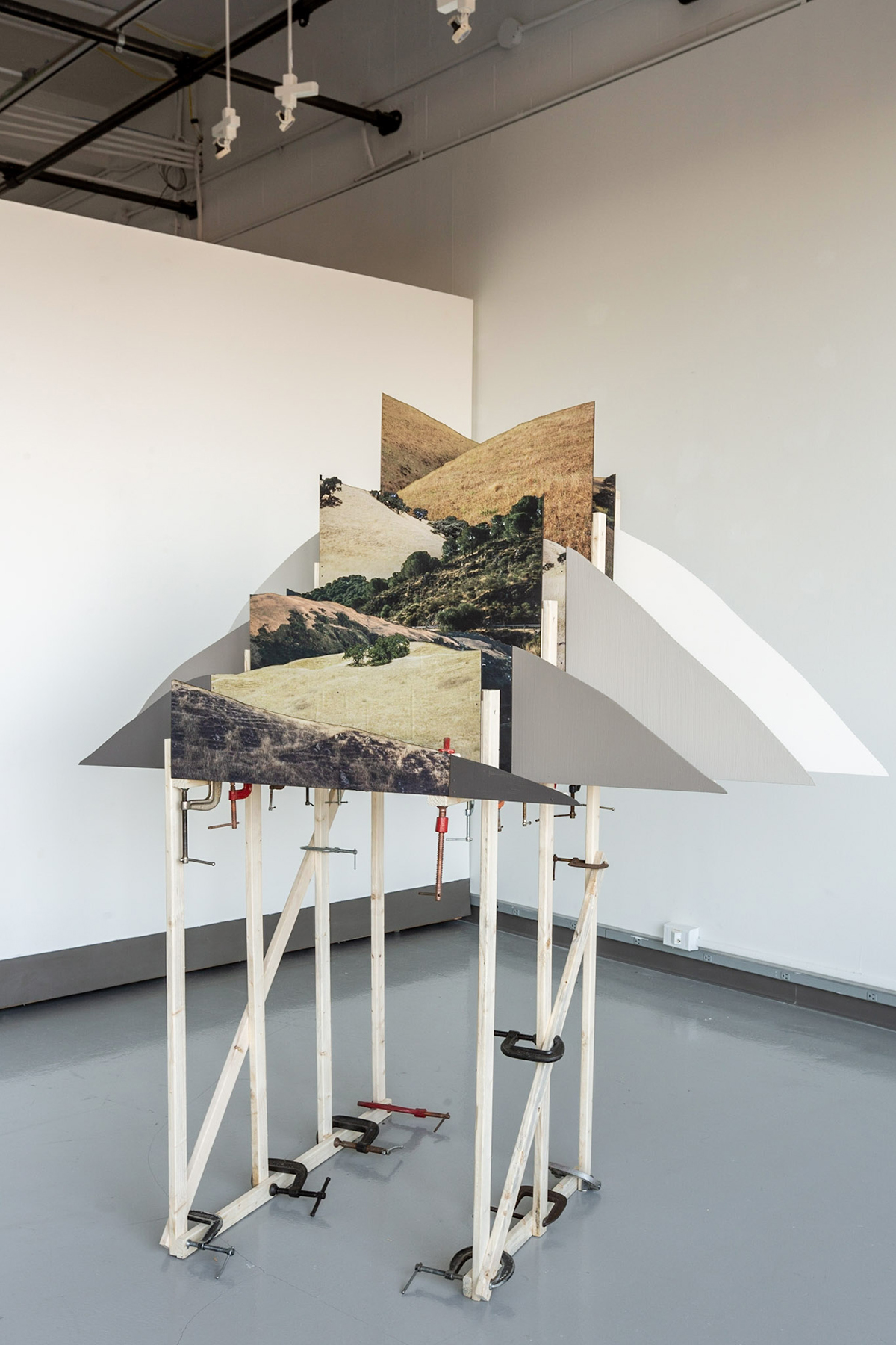 A series of photo prints sits on an intricate easel-type structure.