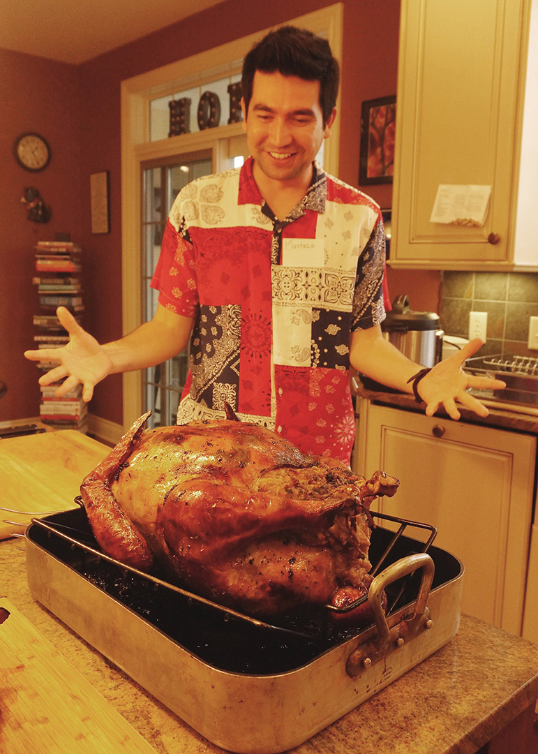 Student looks at whole cooked turkey in pan.