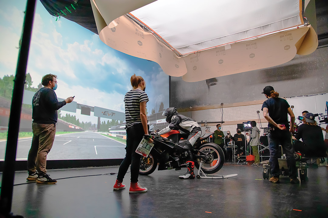 people working in a studio like a movie set with a person on a motorcycle.