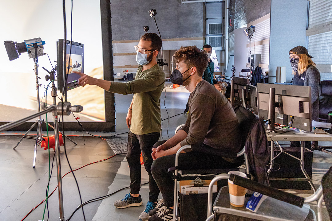 two people looking a scene from a movie on a monitor.