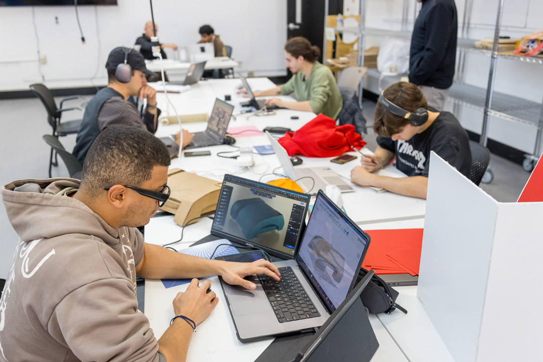 students work on laptops in a brightly lit art studio
