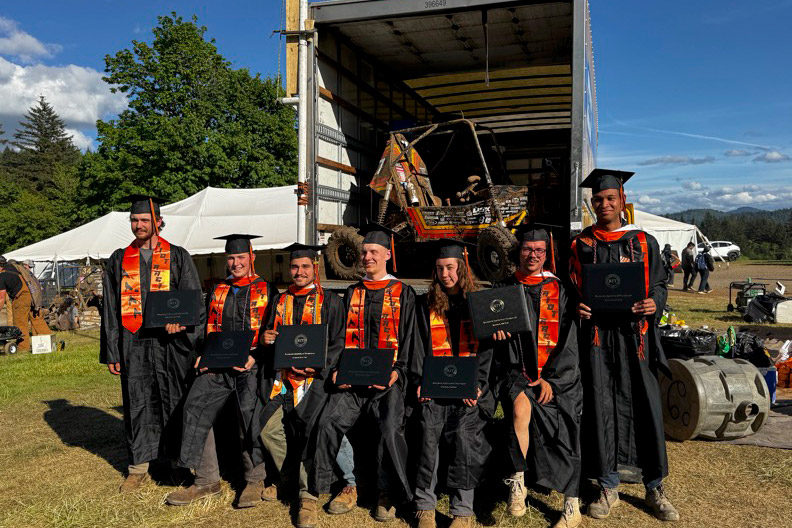 Baja SAE team members pose with diplomas and competition vehicle at graduation.