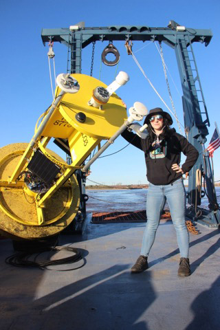 a student stands next to a large yellow machine.