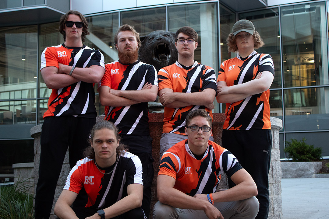The RIT Esports Halo team is shown standing with each other in their team gear in front of the Tiger Statue on campus.