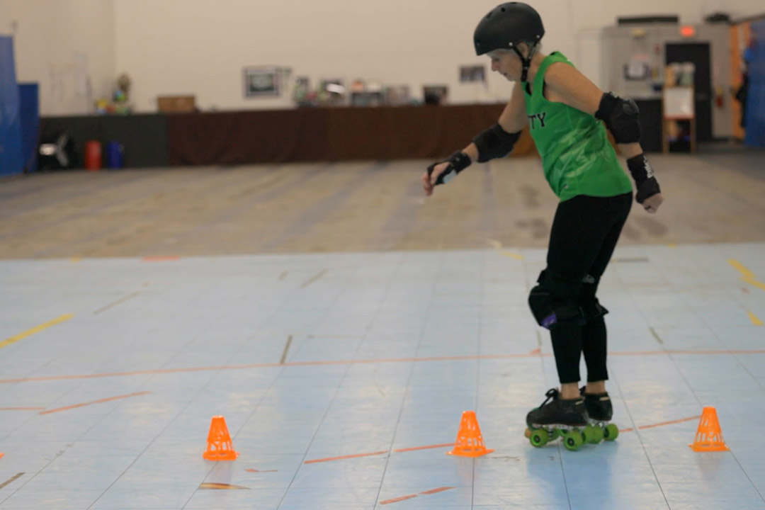 a roller derby skater skates between cones.